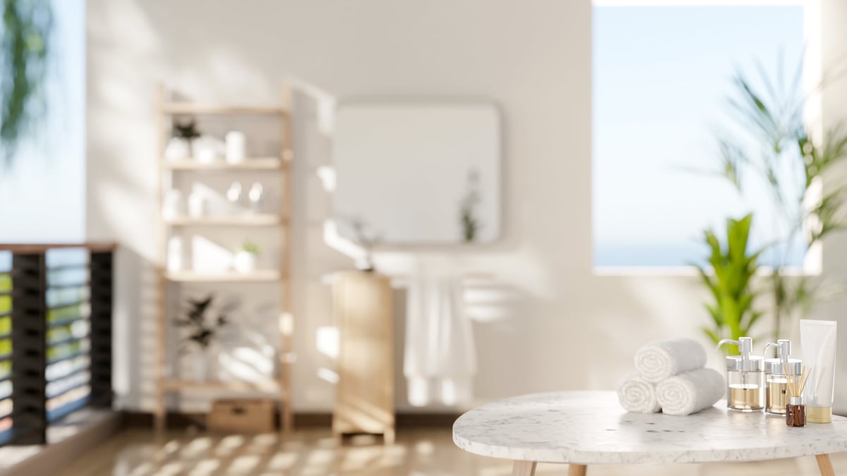 Marble stool table with towels and spa essentials in the wide bathroom with white wall